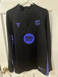Black long-sleeve shirt with logos on a hanger against a white door background