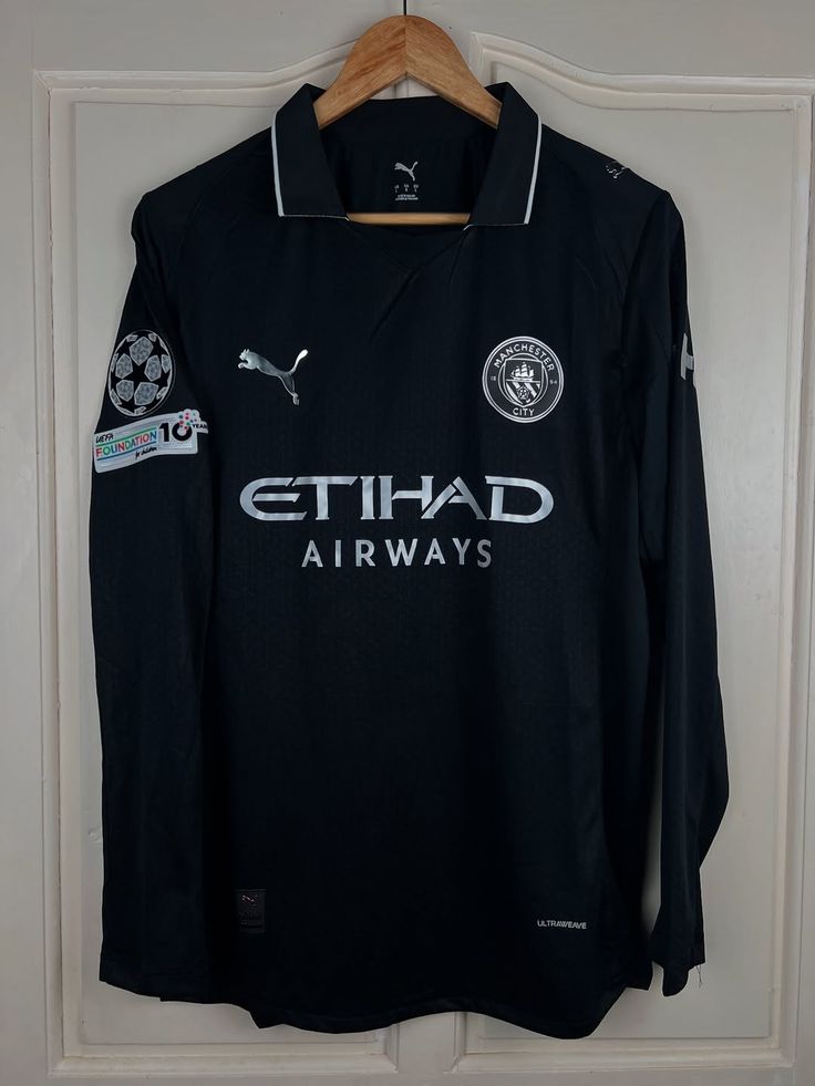 Black sports jersey with branding on a hanger against a white wall